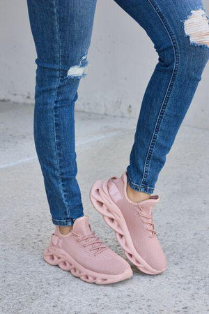 a woman wearing pink sneakers and ripped jeans