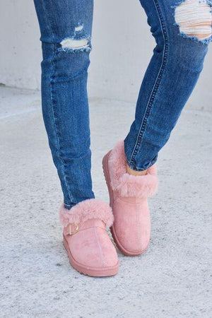 a woman wearing pink slippers and ripped jeans