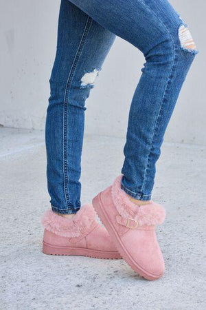 a woman wearing pink slippers and ripped jeans