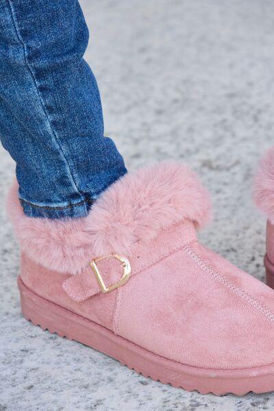 a person wearing pink slippers with a gold buckle