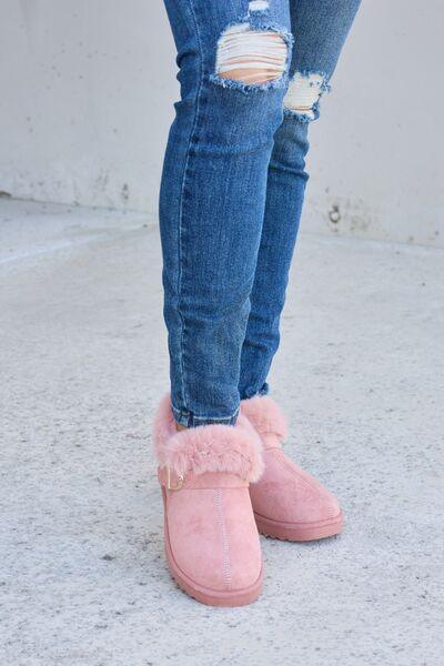 a woman wearing pink boots and ripped jeans