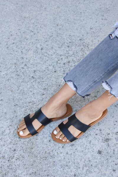 a woman wearing black sandals and ripped jeans
