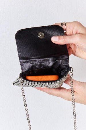 a woman holding a black purse with a chain around it