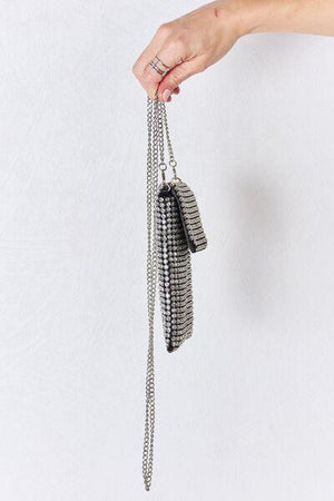 a hand holding a chain with a purse hanging from it