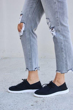a person wearing ripped jeans and black shoes
