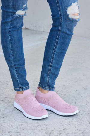 a woman wearing pink shoes and ripped jeans