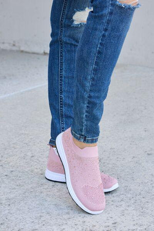 a person wearing pink shoes and ripped jeans