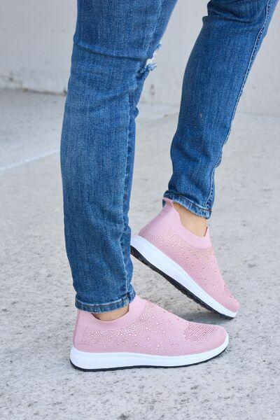 a person standing on a sidewalk wearing pink shoes