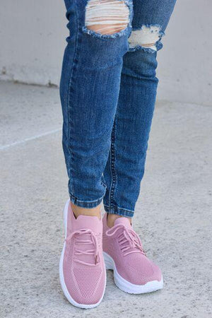 a woman wearing pink sneakers and ripped jeans