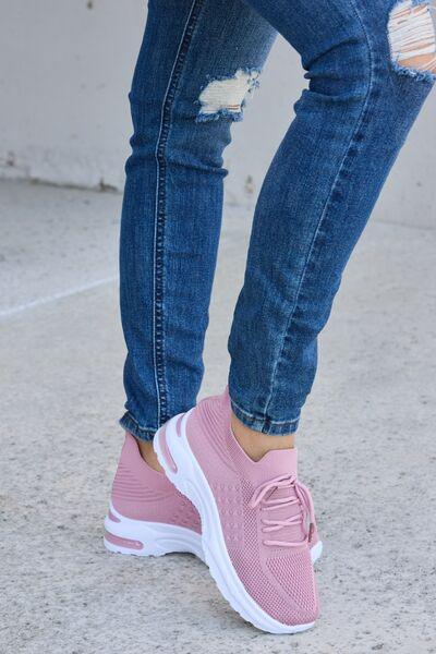 a woman in ripped jeans and pink sneakers