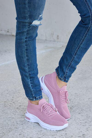 a woman wearing pink sneakers and jeans