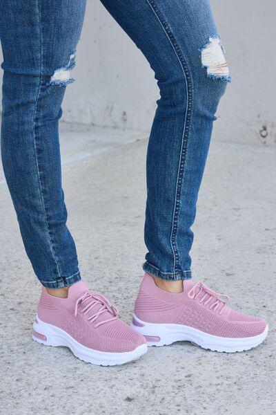 a woman wearing pink sneakers and ripped jeans