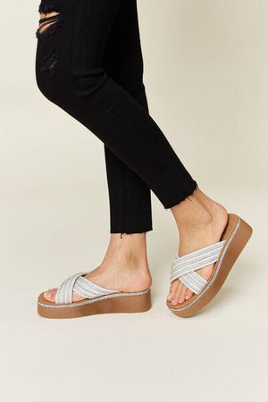 a woman's feet wearing sandals and black jeans