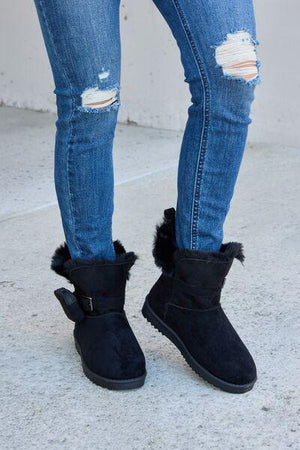 a woman wearing black boots and ripped jeans