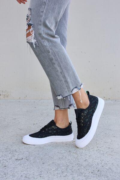 a person in ripped jeans and black sneakers