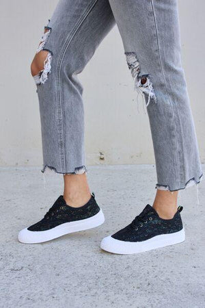 a woman in ripped jeans and black sneakers