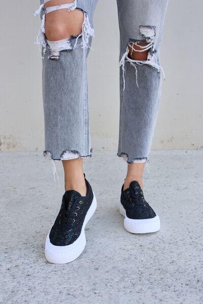 a woman wearing ripped jeans and black sneakers