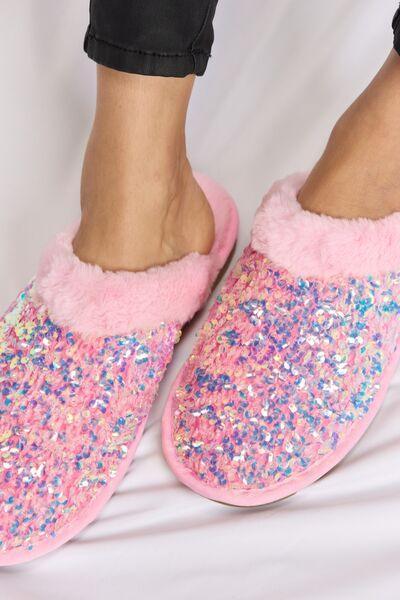 a person wearing pink and blue glitter slippers