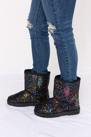 a pair of legs wearing black boots with multicolored sequins
