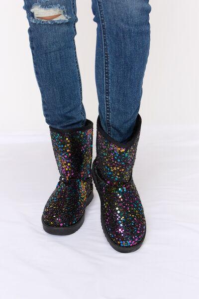 a person wearing black boots with colorful sequins