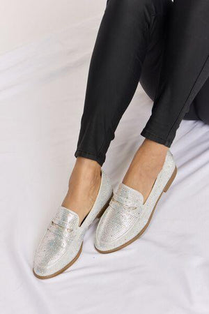 a person sitting on a bed wearing silver shoes