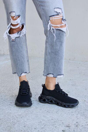 a person wearing ripped jeans and black sneakers