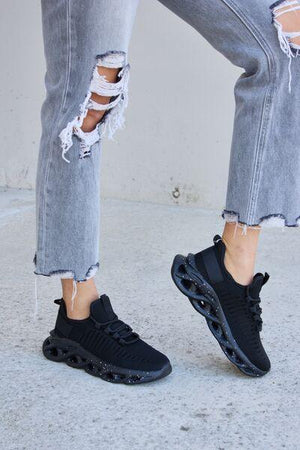 a person in ripped jeans and black sneakers