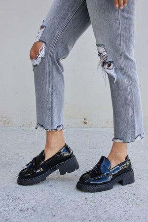 a woman in ripped jeans and black shoes