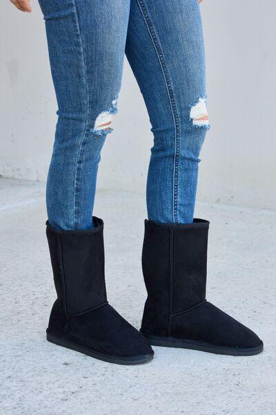 a woman wearing black boots and ripped jeans