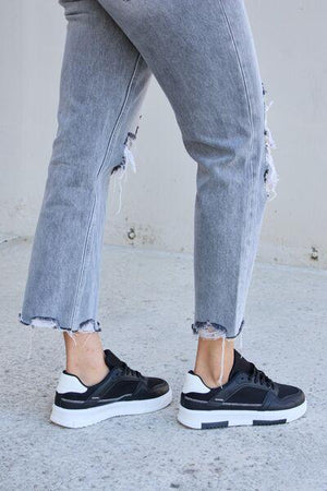 a person wearing ripped jeans and black sneakers