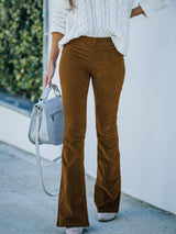 a woman wearing brown pants and a white sweater