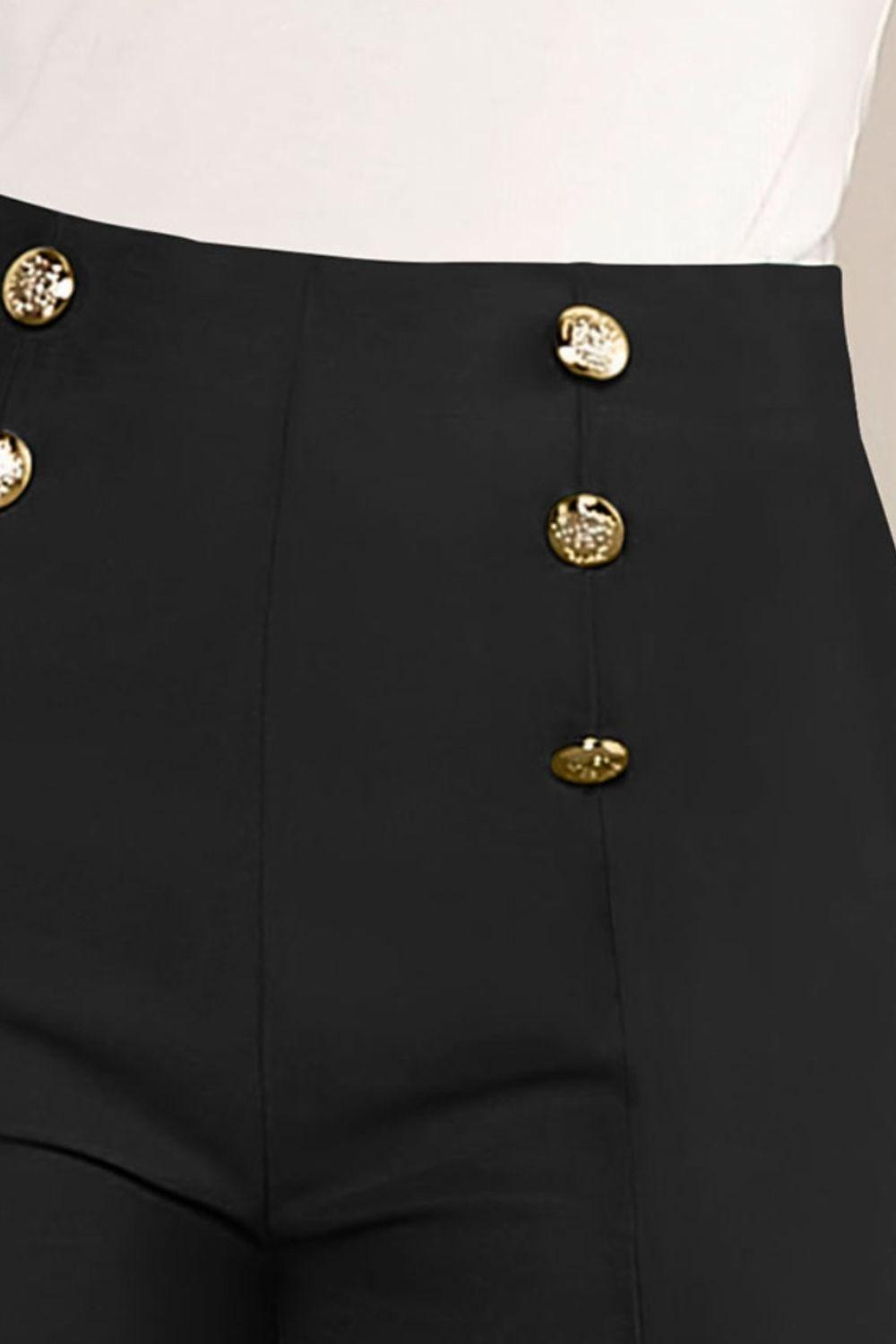 a woman wearing black pants with gold buttons