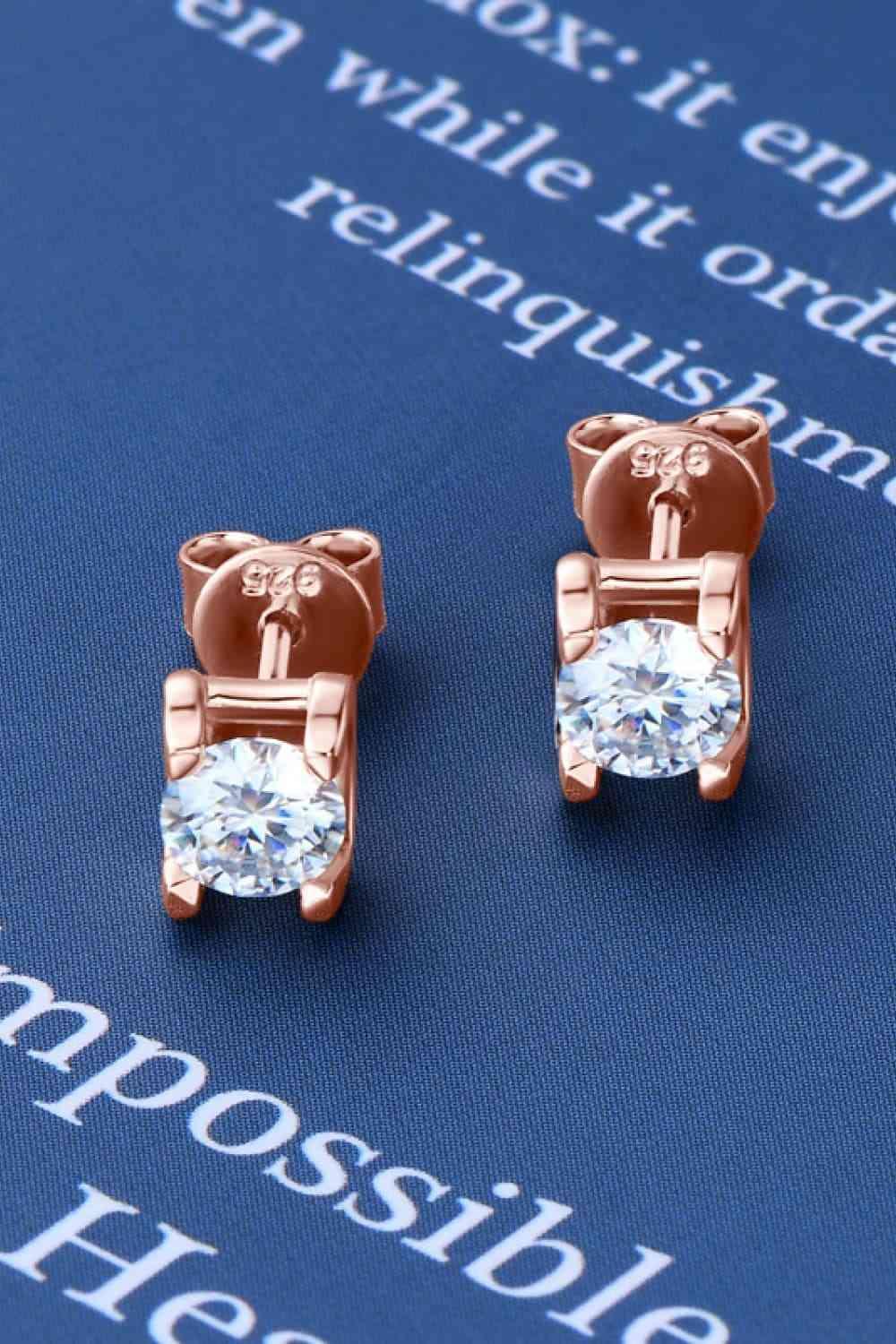 a pair of teddy bear stud earrings on a blue background