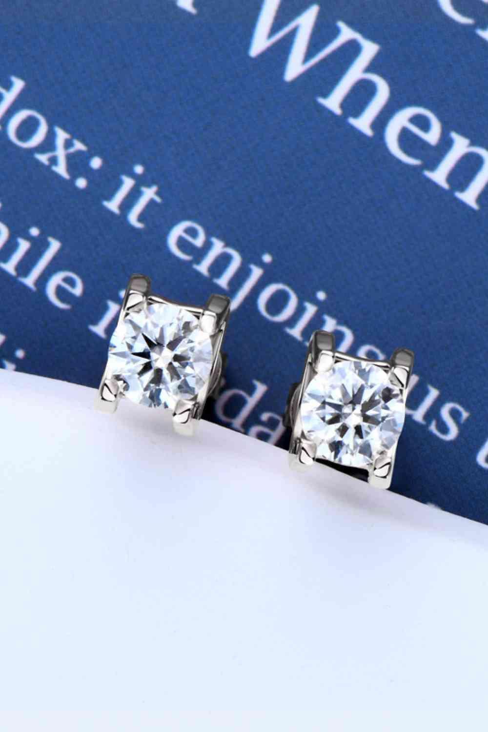a pair of diamond earrings sitting on top of a book