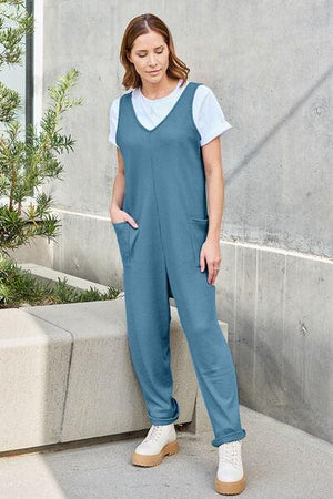 a woman in a blue jumpsuit standing next to a cement wall