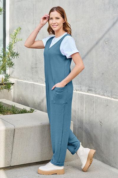 a woman in a blue jumpsuit is posing for a picture