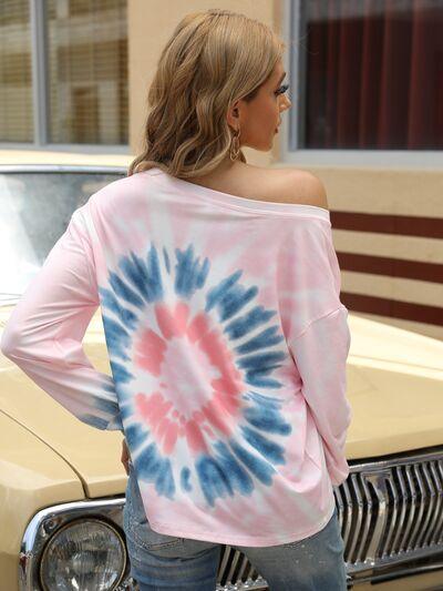 a woman standing in front of a car wearing a pink and blue tie - dyed