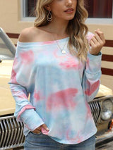 a woman standing in front of a car wearing a tie dye top