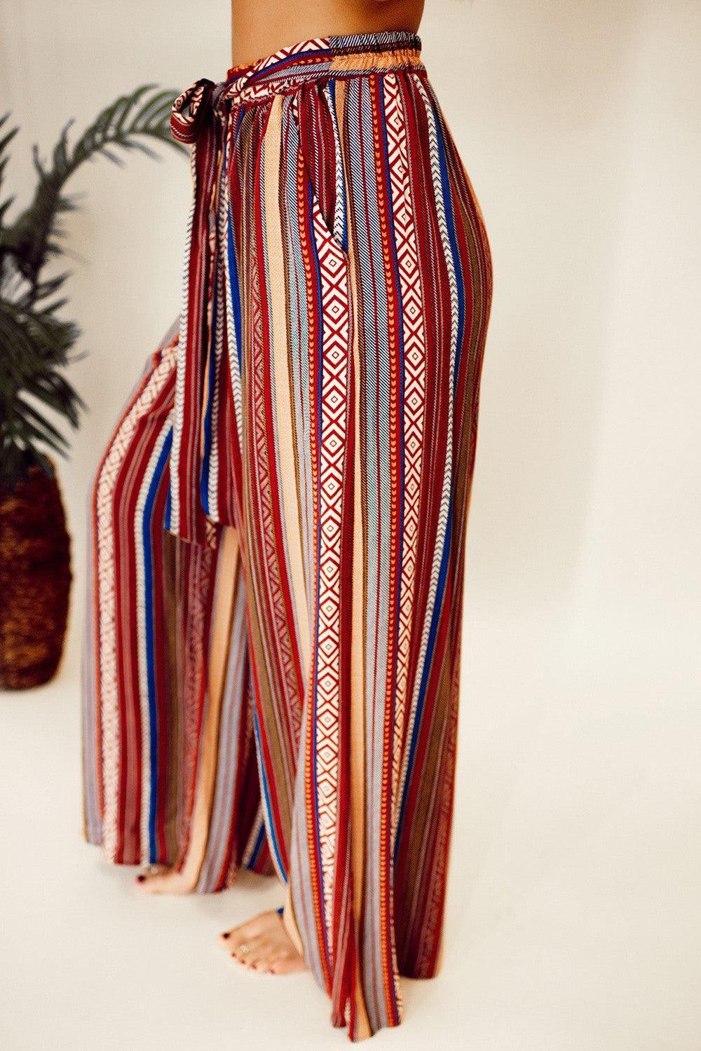 a woman wearing a striped pants with a pine tree in the background