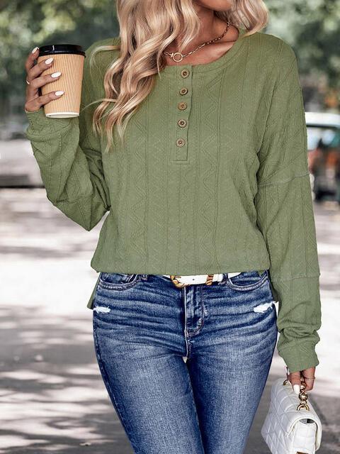 a woman holding a cup of coffee and wearing a green top