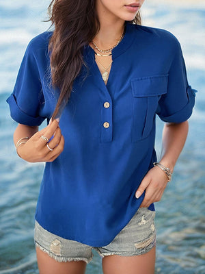 a woman standing in the water wearing a blue shirt