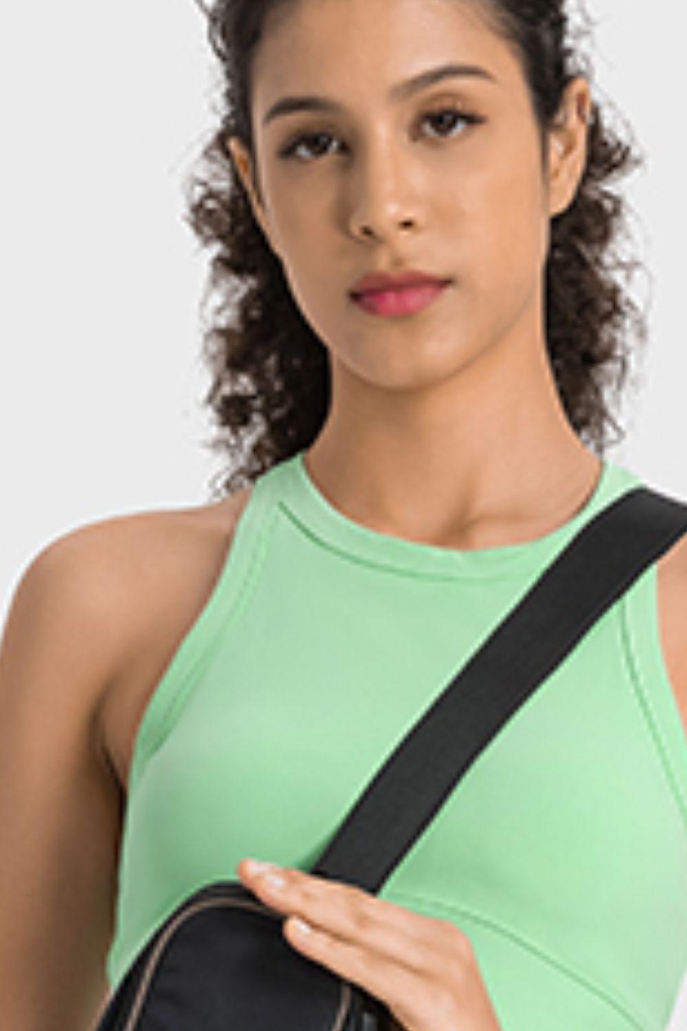 a woman in a green tank top holding a black bag