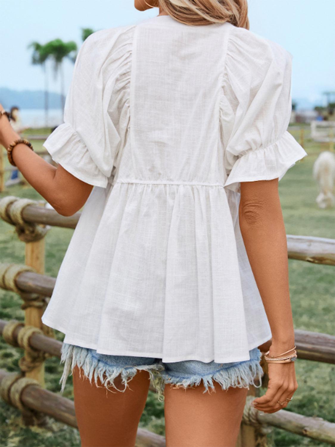 a woman wearing a white blouse and denim shorts