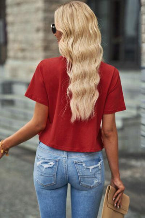 a woman with long blonde hair wearing a red shirt and jeans