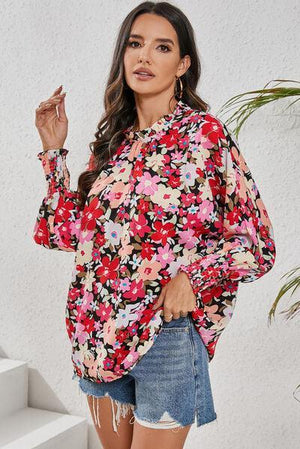 a woman wearing a floral blouse and denim shorts