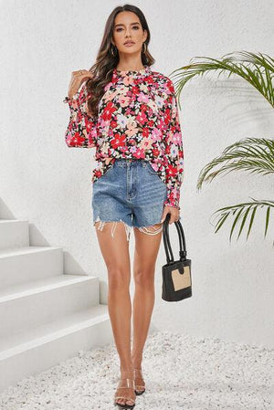 a woman wearing a floral top and denim shorts