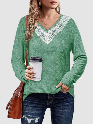 a woman holding a cup of coffee wearing a green sweater