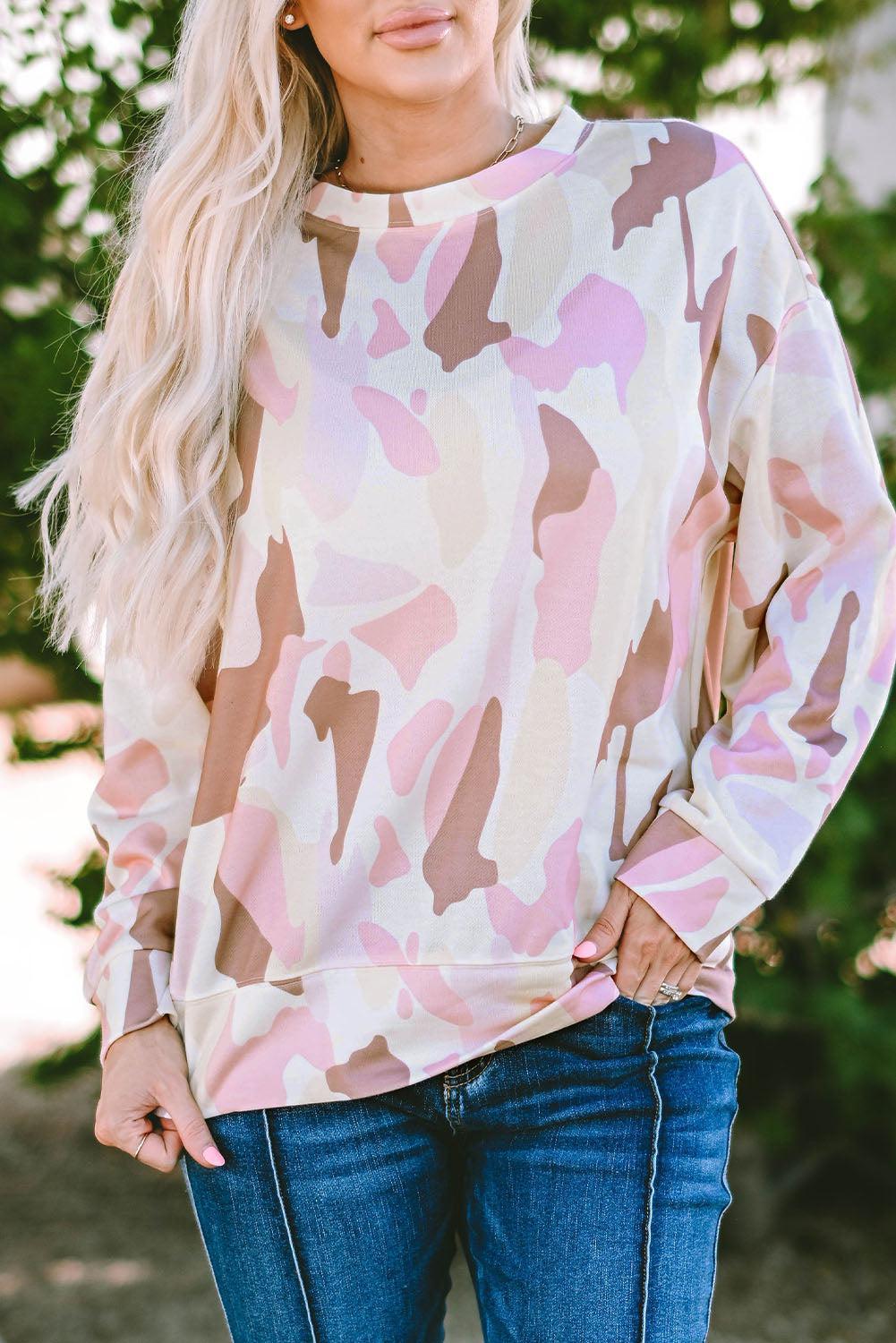 a woman wearing a pink camo sweatshirt and jeans