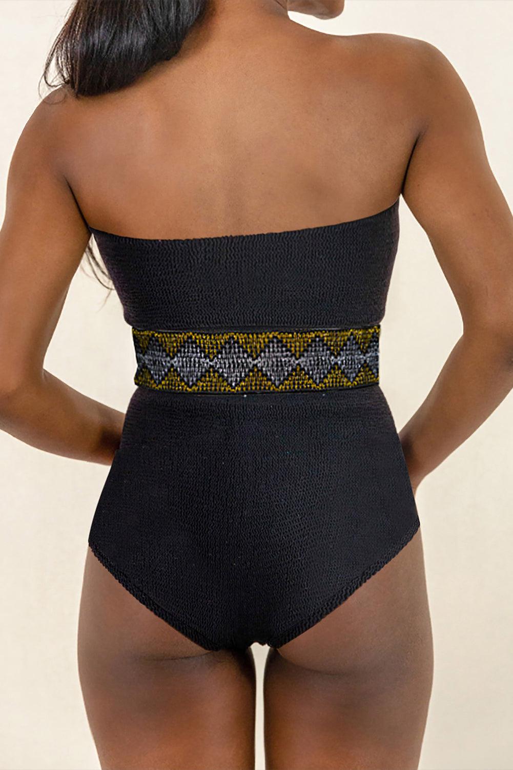 a woman in a black swimsuit with a gold belt