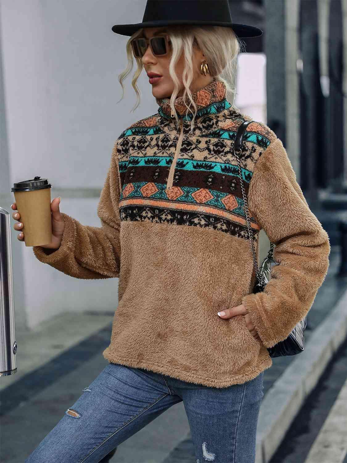 a woman in a hat and sweater holding a cup of coffee